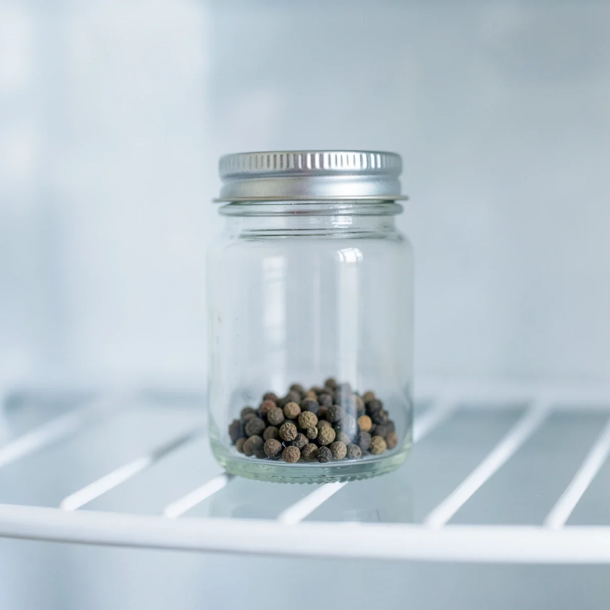 Cannabis seeds stored in a sealed glass jar inside a refrigerator for long-term keeping