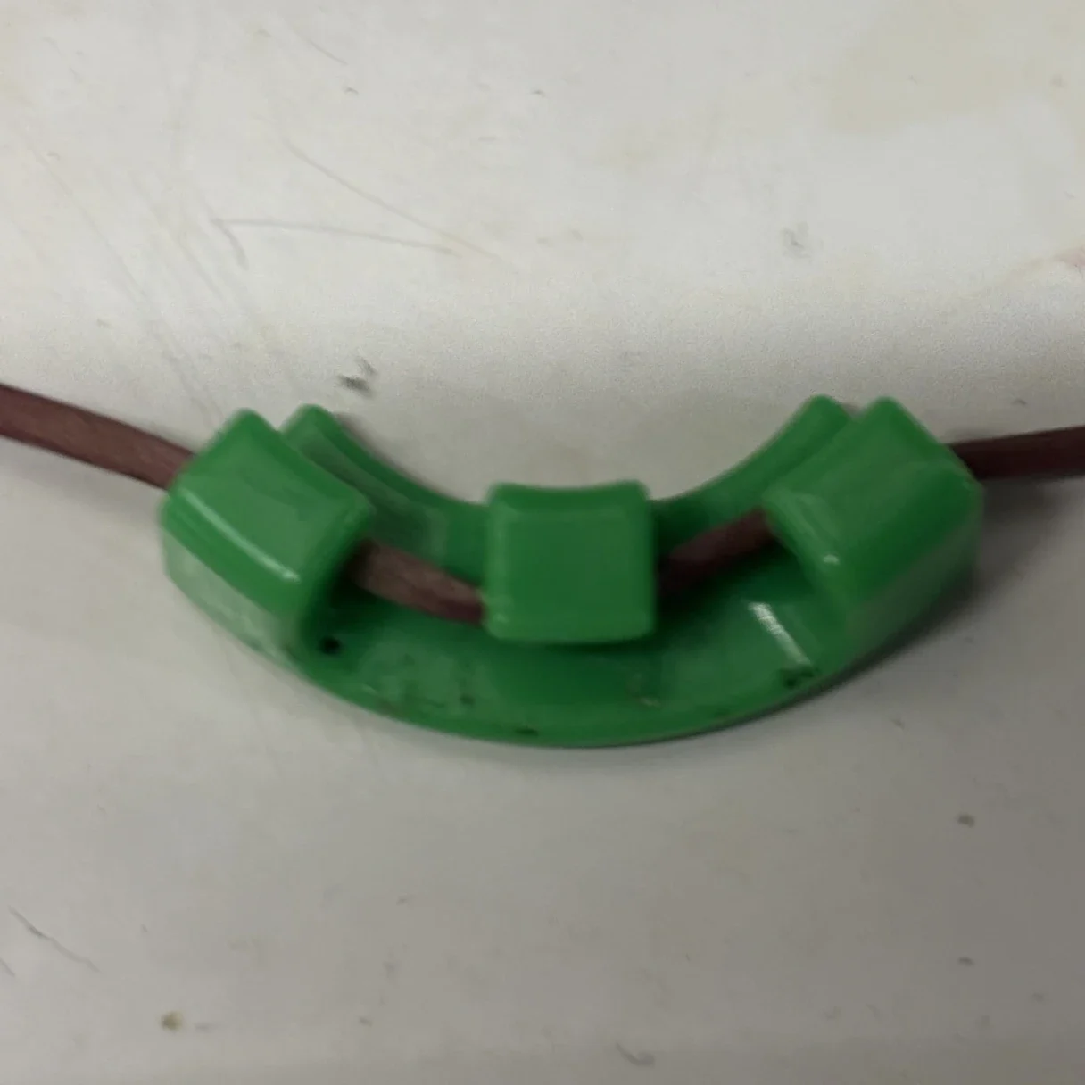 A green Lighthouse LST clip holding a stem bent at a right angle during low stress training
